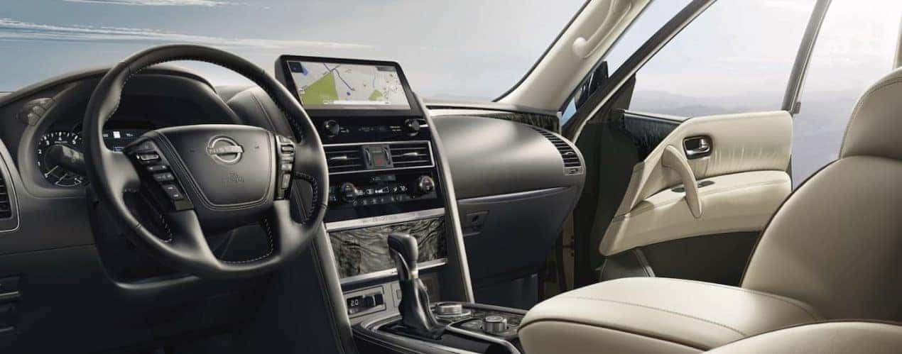 The black and white interior of a 2023 Nissan Armada shows the steering wheel and infotainment screen.