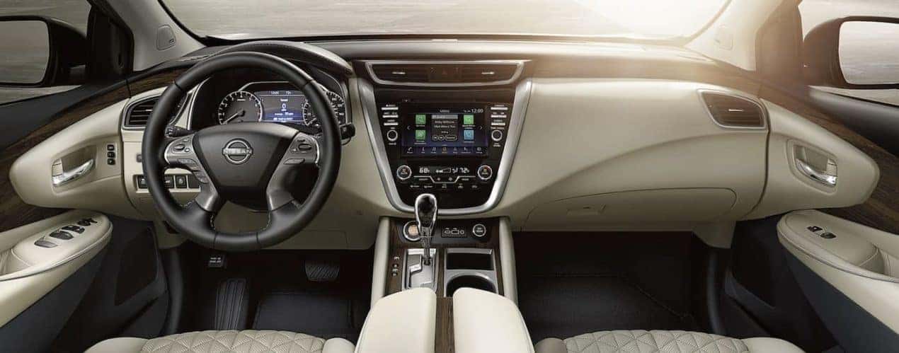 The white and black interior of a 2023 Nissan Murano shows the steering wheel and infotainment screen.