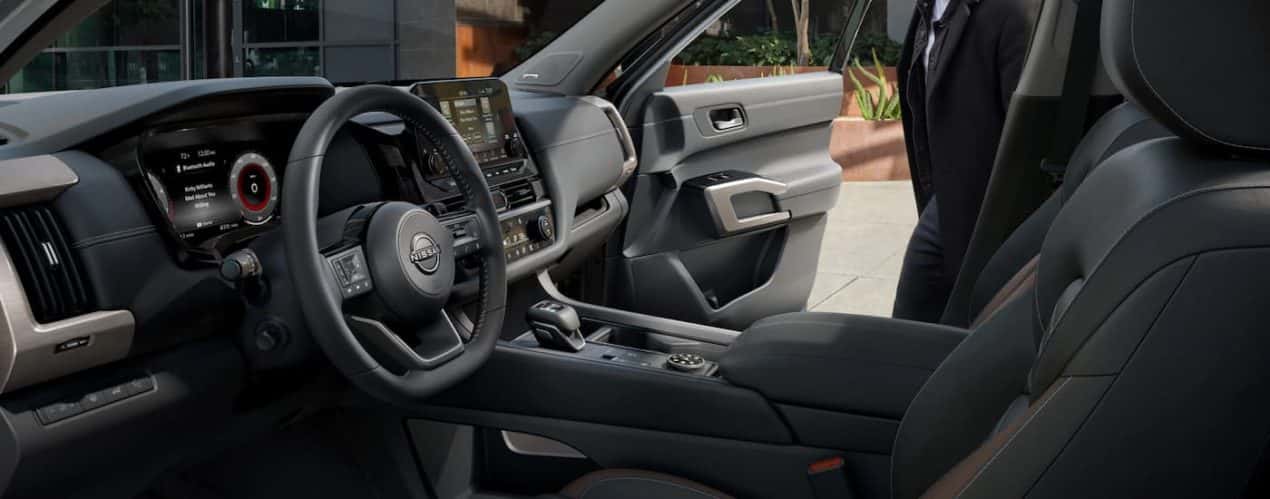 A man is shown getting into the passenger side of a 2023 Nissan Pathfinder Platinum.