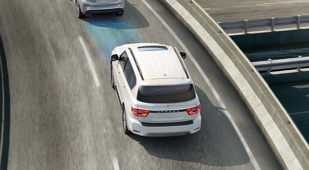 A white 2023 Nissan Armada Platinum is shown with a simulated sensor on a city road.