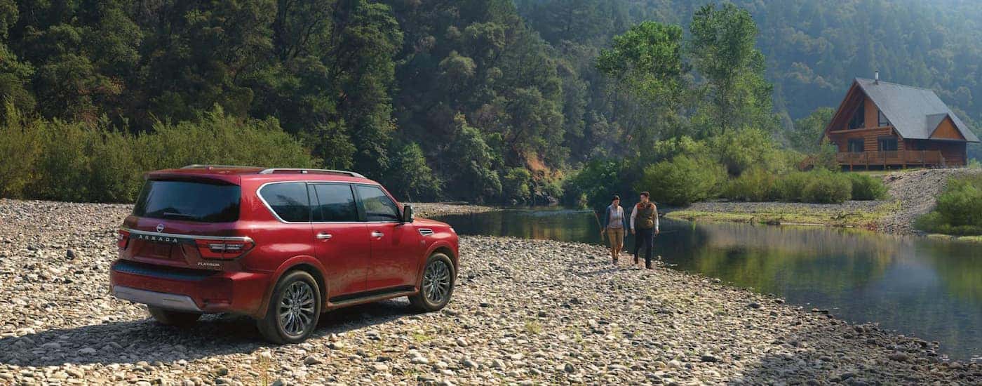 A red 2023 Nissan Armada is shown from a rear angle parked next to a small river.