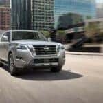 A silver 2023 Nissan Armada drives down an open city highway during the day