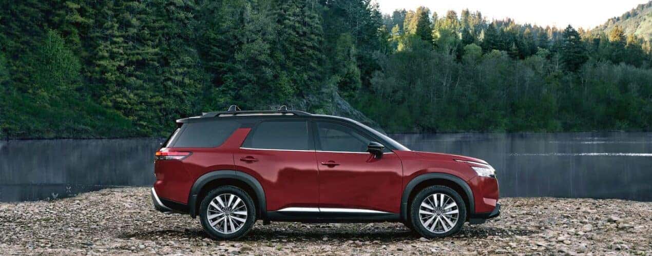 A red 2023 Nissan Pathfinder Platinum is shown from the side parked near a river.