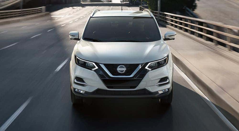 A white 2021 Nissan Rogue Sport is shown driving on a bridge.