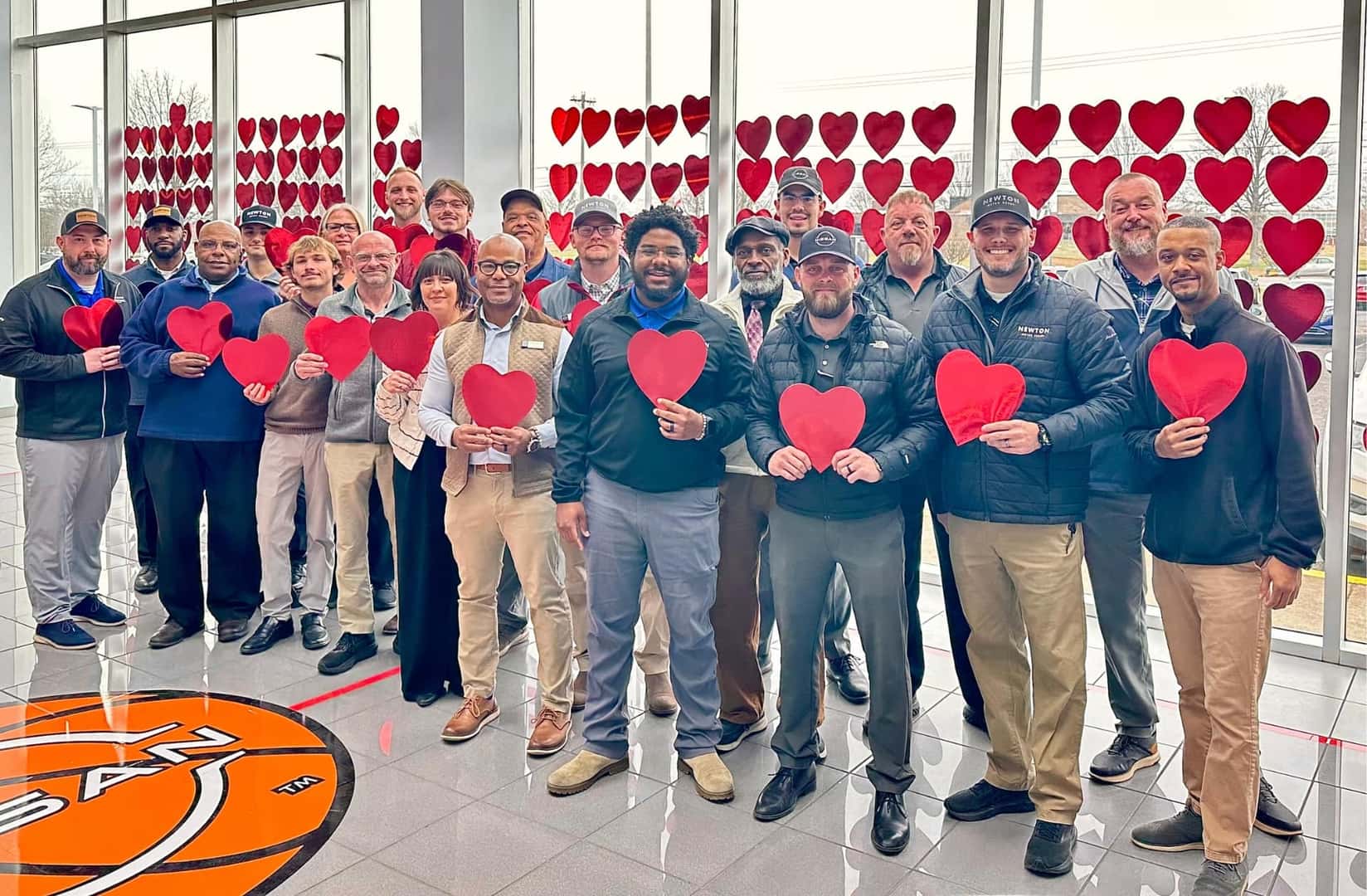 newton nissan sales team hold hearts representing the donation they made on behalf of heart disease in February 2026