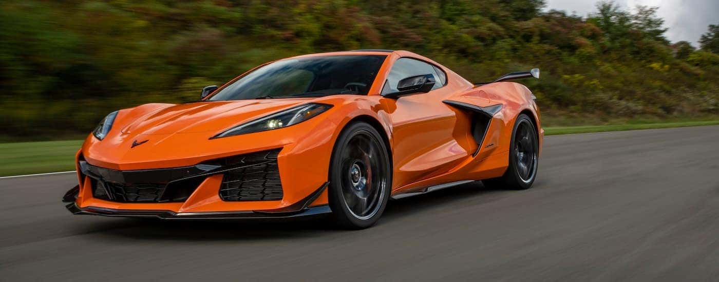 An orange 2023 Chevy Corvette Z06 is shown driving on an open road after leaving a Chevrolet dealer in Monroe, LA.