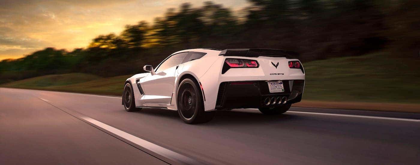 A white 2015 Chevy Corvette Z06 is shown from the rear driving on a open road.