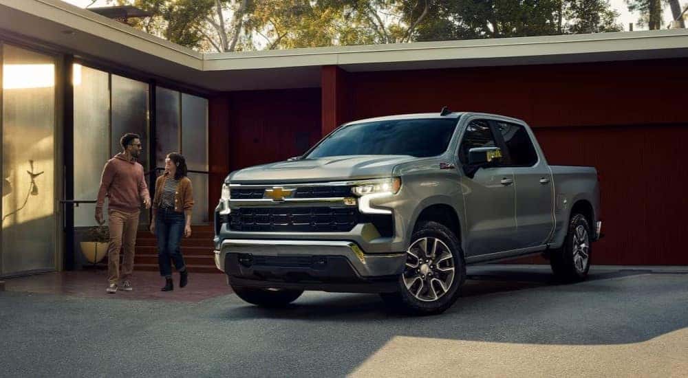 A silver 2023 Chevy Silverado 1500 Z71 is shown parked in front of a modern house.
