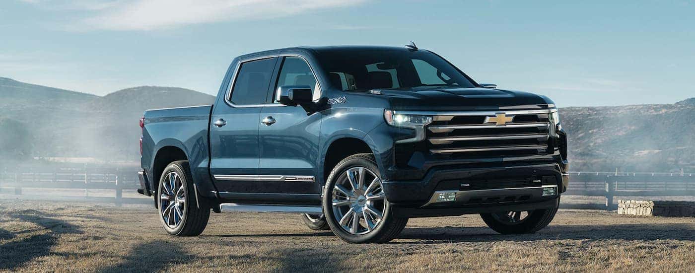 A blue 2022 Chevy Silverado 1500 High Country for sale is shown parked in an open field.