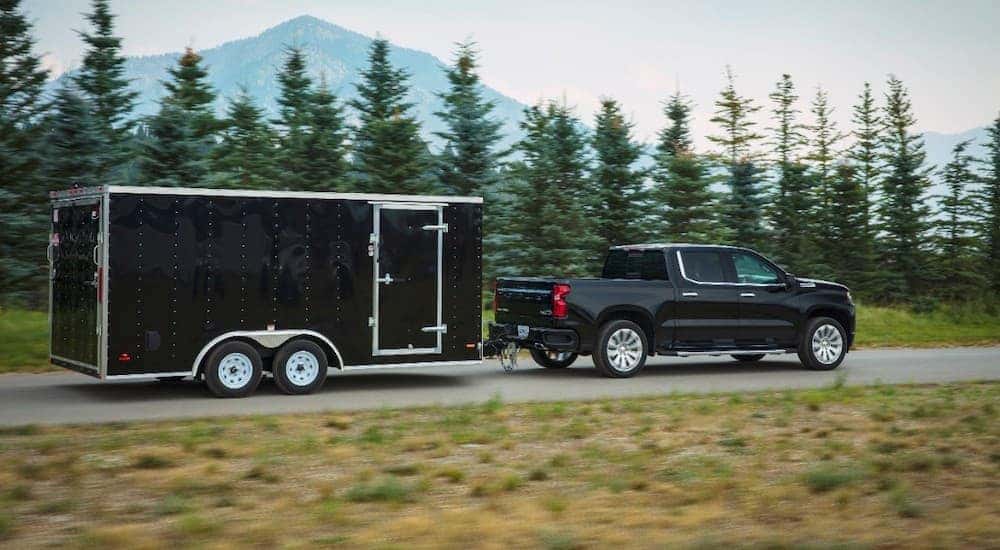 A black 2019 Chevy Silverado 1500 High Country is shown towing a trailer.