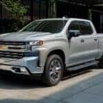 A popular used Chevy Silverado for sale, a silver 2019 Chevy Silverado 1500, is shown parked near a store.