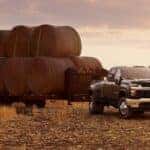 A black 2023 Chevy Silverado 3500 HD is shown from the front at an angle while hauling hay on a trailer.
