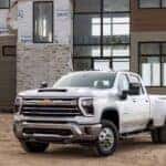 A white 2024 Chevy Silverado 3500 HD LTZ is shown from the front at an angle after leaving a dealer that has heavy duty trucks for sale.