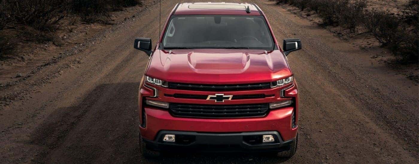 A red 2023 Chevy Silverado 1500 RST is shown driving on a dirt road.