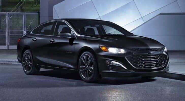 A black 2024 Chevy Malibu is shown parked near a building after visiting a Chevy dealer near Claiborne.