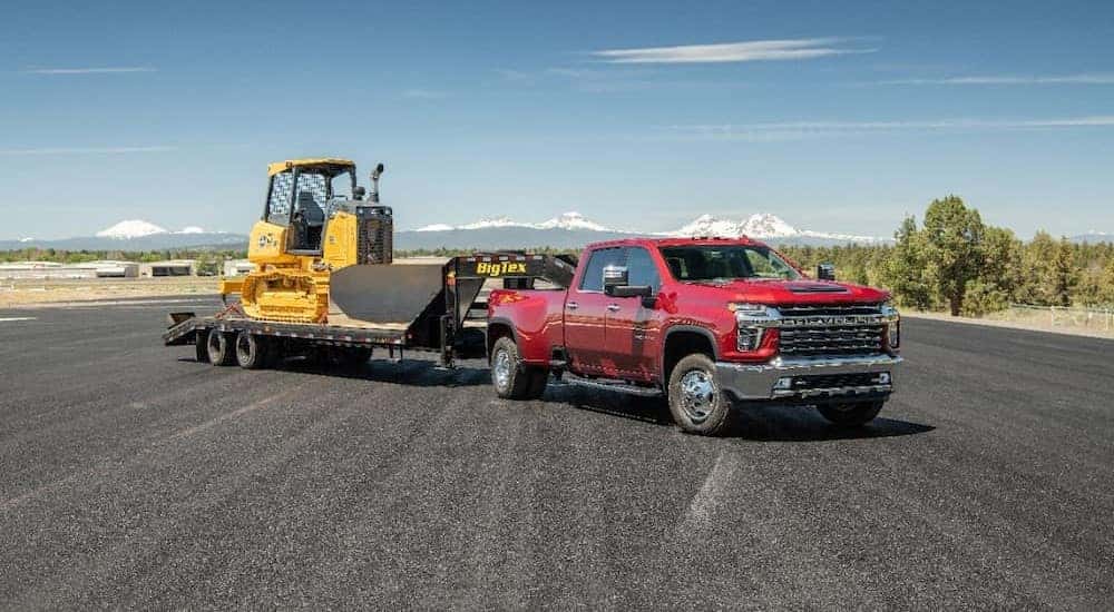 A red 2021 Chevy Silverado 3500HD is shown parked while towing a trailer.