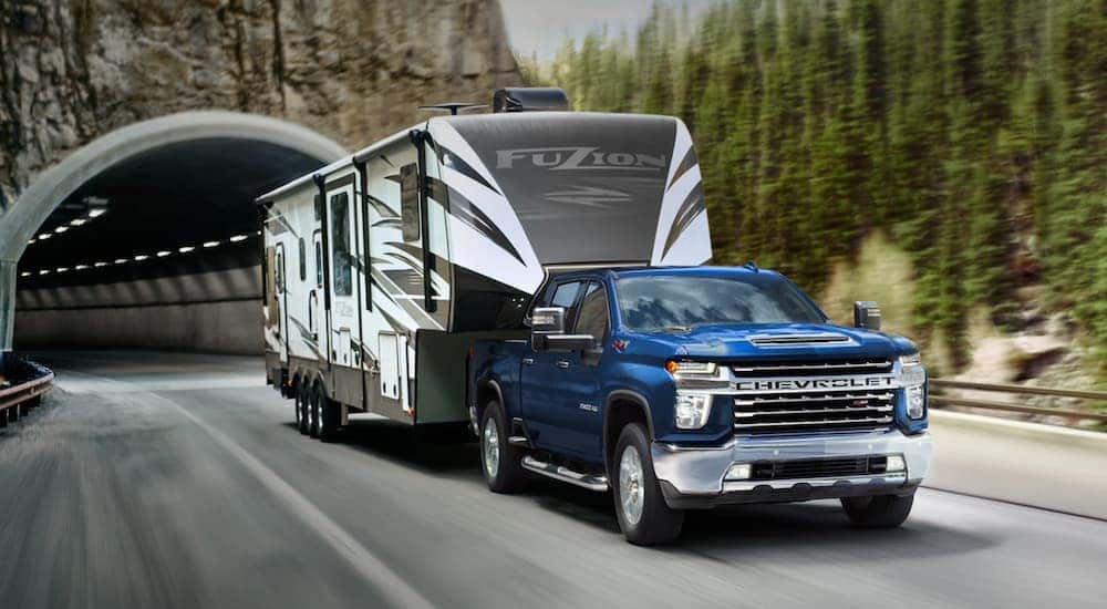 A blue 2021 Chevy Silverado 2500HD is shown towing a camper after viewing a used Chevy Silverado for sale near Swartz.