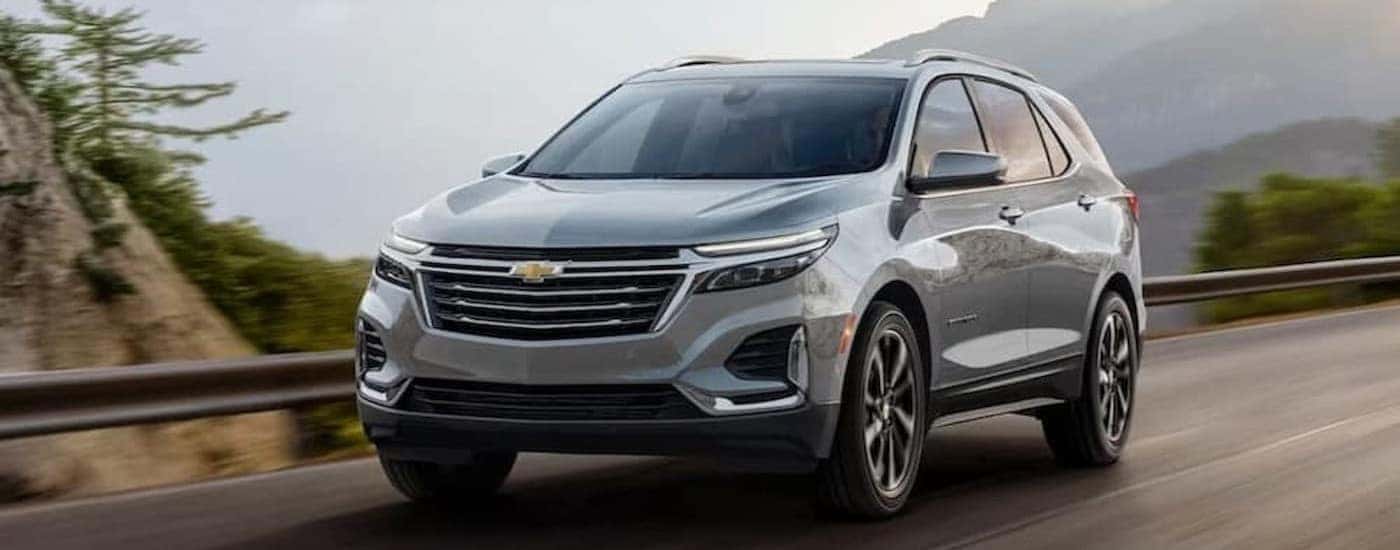 A silver 2024 Chevy Equinox for sale is shown driving on a highway.