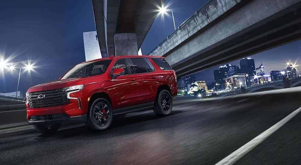 A red 2024 Chevy Tahoe is shown driving to view a used Chevy Tahoe for sale.