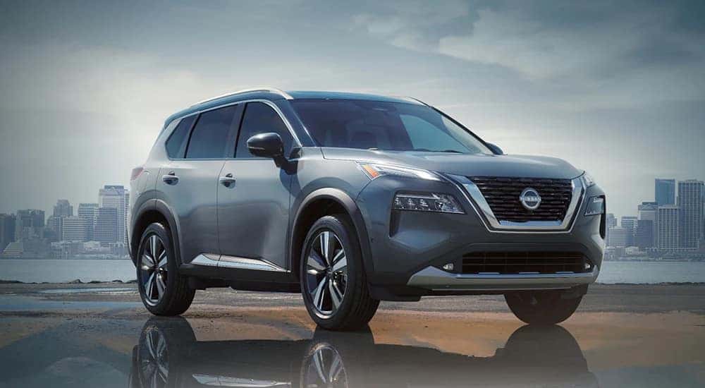 A silver 2024 Nissan Rogue parked in front of a cityscape.