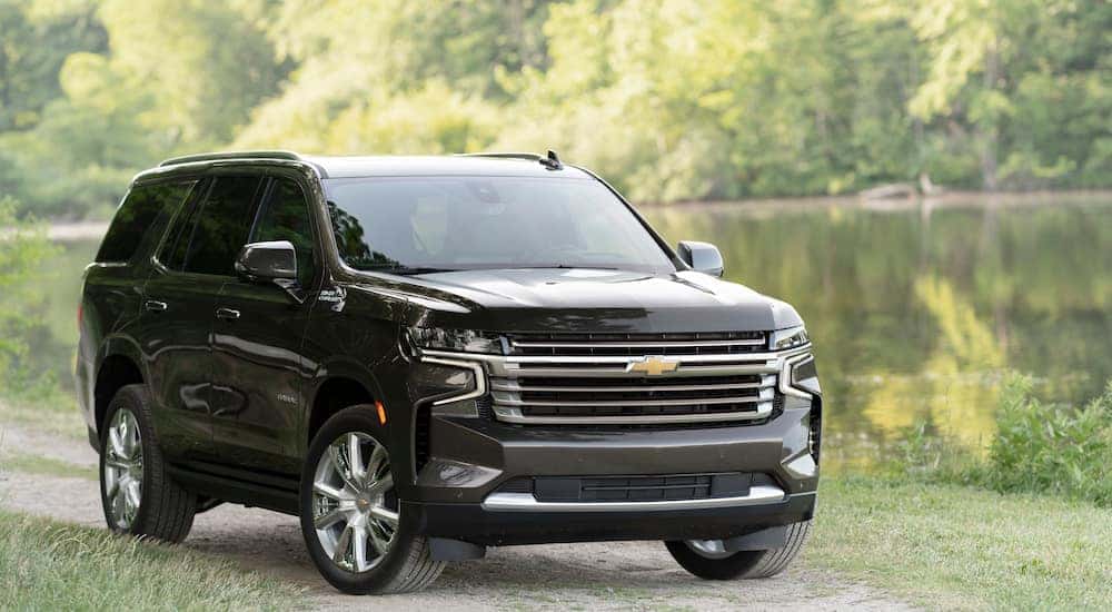 A dark green 2021 Chevy Tahoe High Country parked next to a lake.