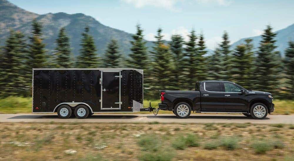 A black 2019 Chevy Silverado 1500 High Country is shown towing a trailer.