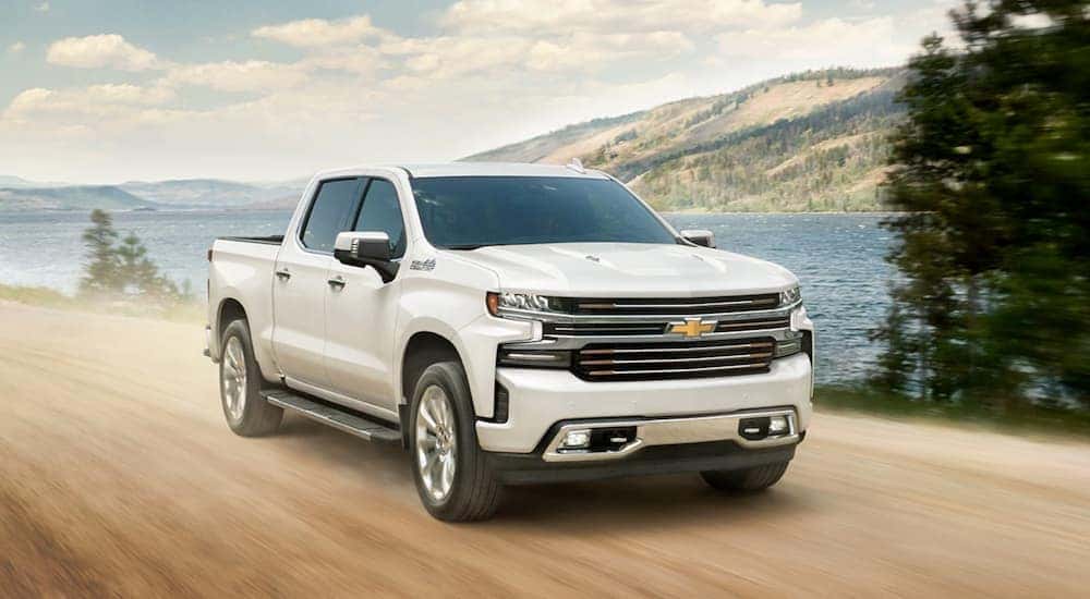 A white 2020 Chevy Silverado 1500 High Country is shown driving near a lake.