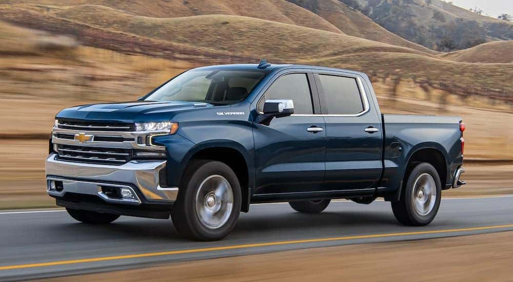 A blue 2021 Chevy Silverado 1500 is shown driving after viewing used trucks for sale.