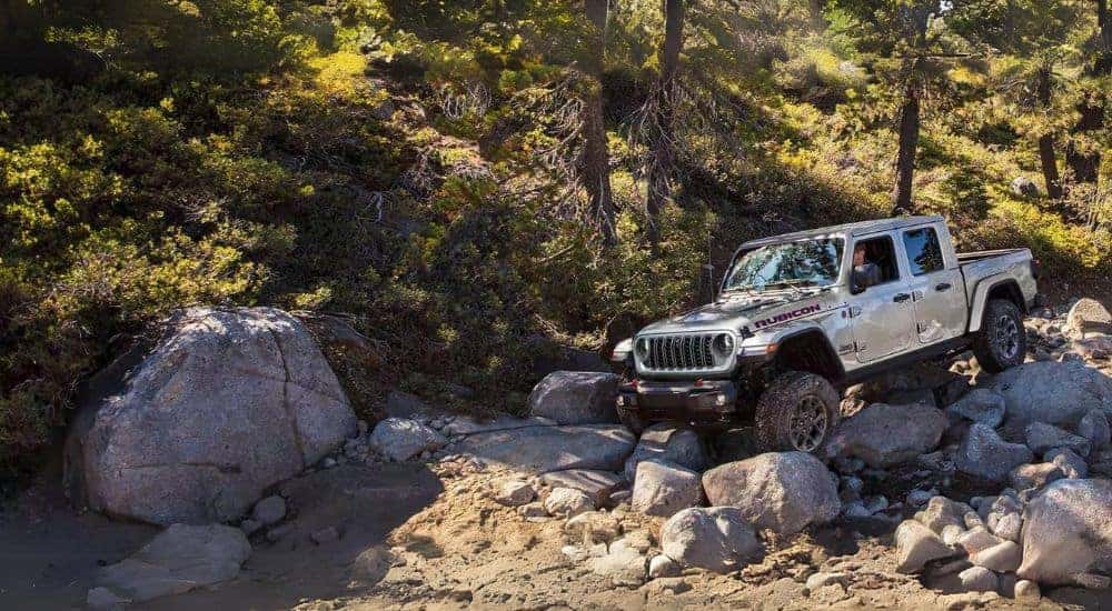 A white 2024 Jeep Gladiator Rubicon driving over a rocky hill.