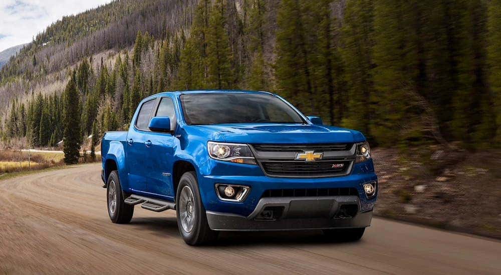 A blue 2020 Chevy Colorado driving around a bend. 