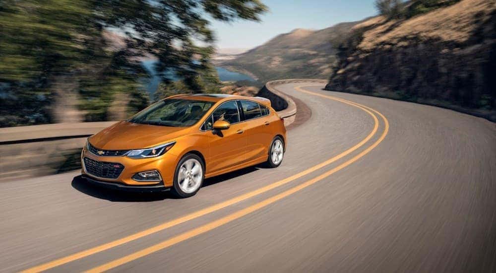 An orange 2018 Chevy Cruze RS is shown driving on a highway.