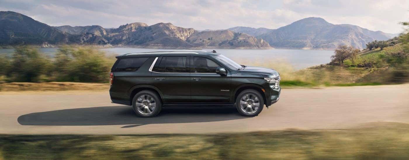 A black 2022 Chevy Tahoe High Country is shown driving near a lake.