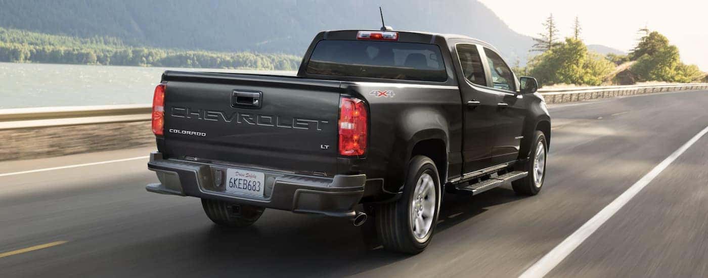 Rear angle view of a black 2022 Chevy Colorado LT driving down a road.