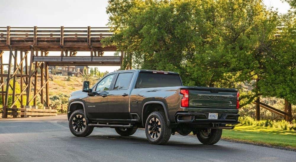 A grey 2020 Chevy Silverado 2500 HD Custom is shown from the rear at an angle after leaving a dealer that has used trucks for sale near me.