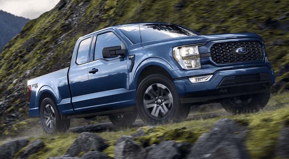 A blue 2021 Ford F-150 is shown from the front at an angle after leaving a dealer that has used trucks for sale near me.