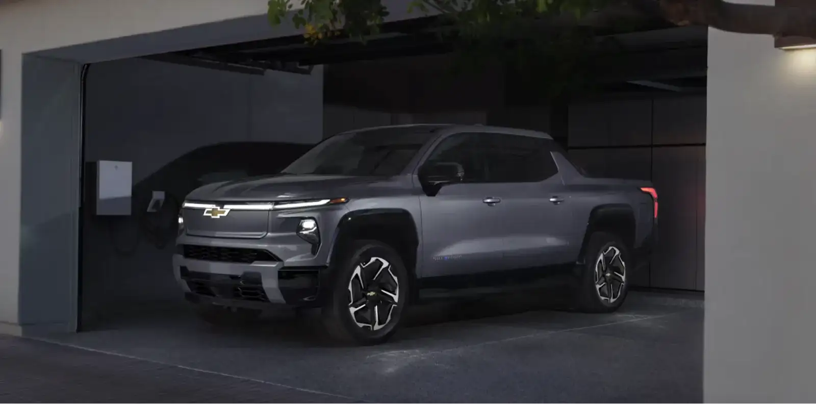 The 2026 Chevrolet Silverado EV parked in a home garage next to a wall-mounted charger