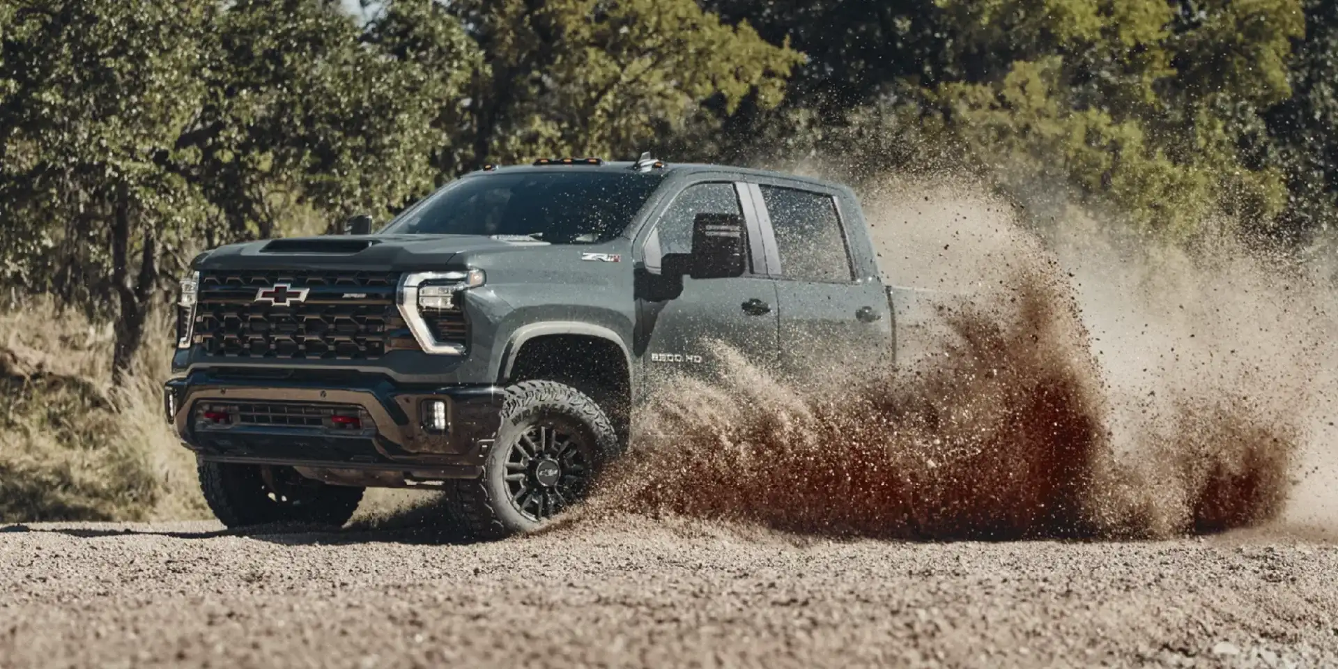 The 2026 Chevy Silverado 2500 HD ZR2 kicking up dirt on an off-road trail