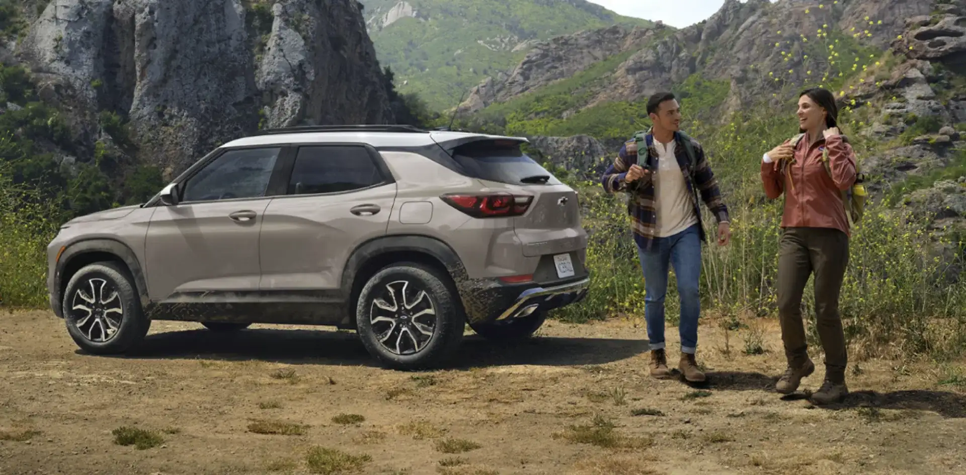 The 2026 Chevy Trailblazer parked at a mountain trailhead with two hikers walking up beside it