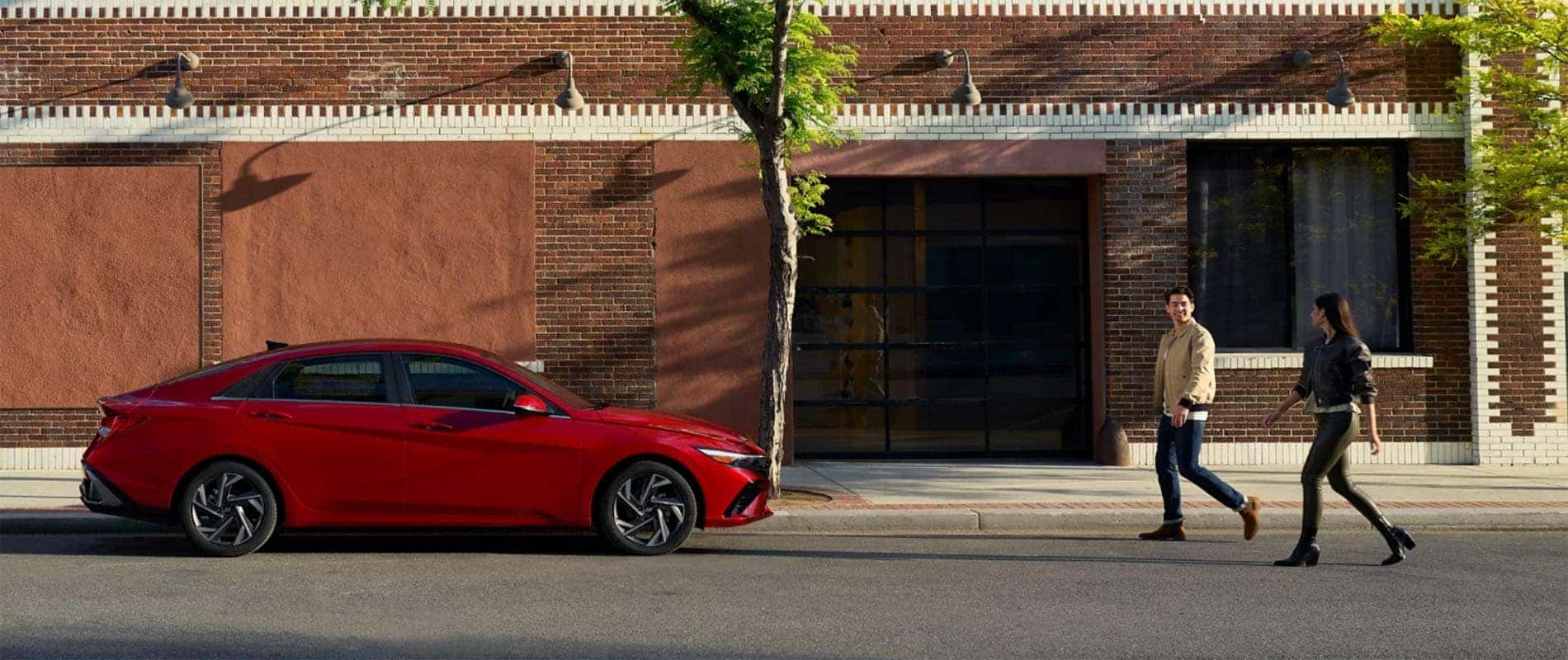 Two people walking towards a Hyundai Elantra