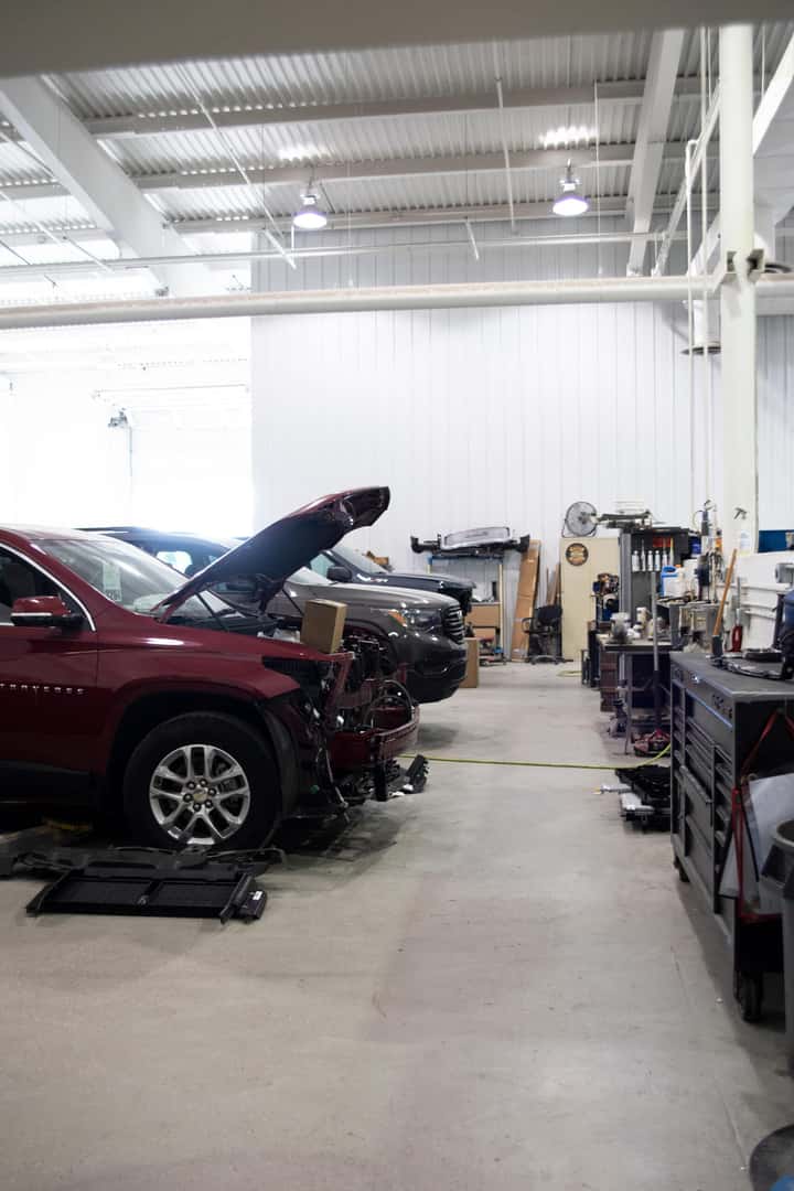 Vehicles with hood up in body shop