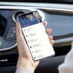 person_holding_phone_with_Buick_Connected_Services_app_in_car_o