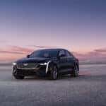 2026 Cadillac CT4 in a Black Raven paint driving in a sandy terrain