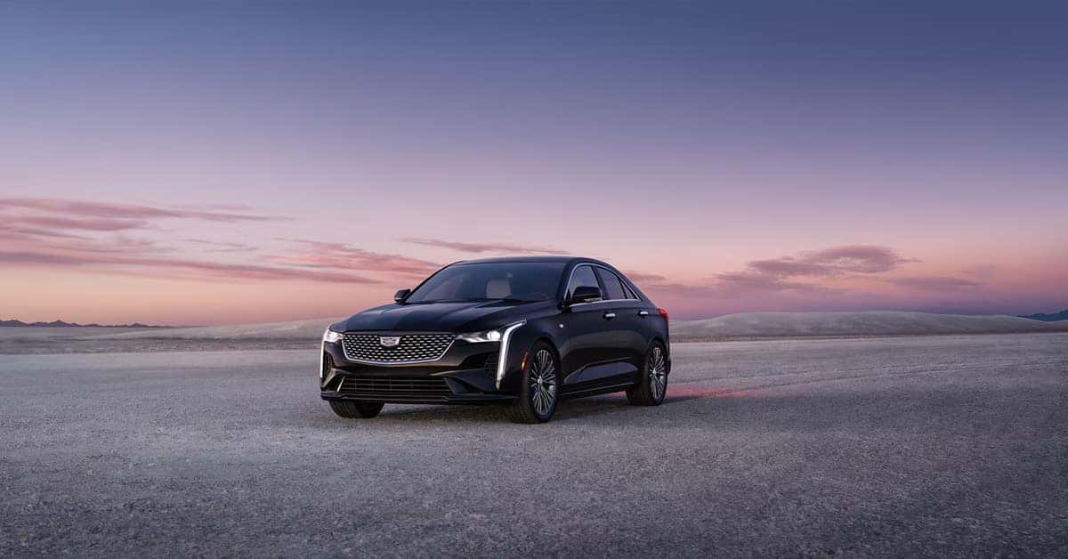2026 Cadillac CT4 in a Black Raven paint driving in a sandy terrain